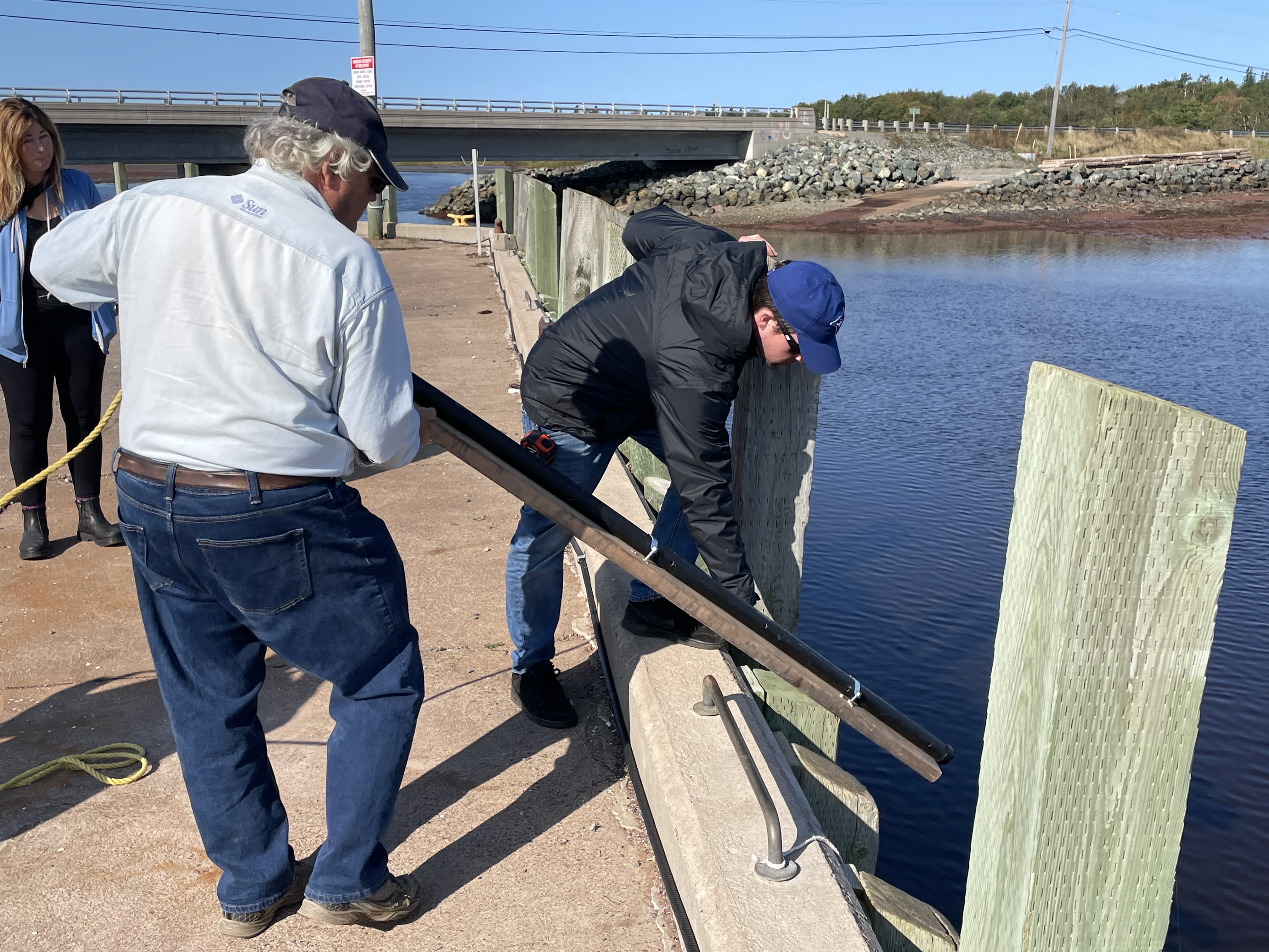 Tim Webster from NSCC, Steve Ferguson and Maggie Pitts from the Municipality of Cumberland look over a gauge that was placed in Northport Harbour as part of a research project that will measure tides and storm surges to help predict coastal vulnerability along the Northumberland Strait in Cumberland County. Darrell Cole – Municipality of Cumberland photo