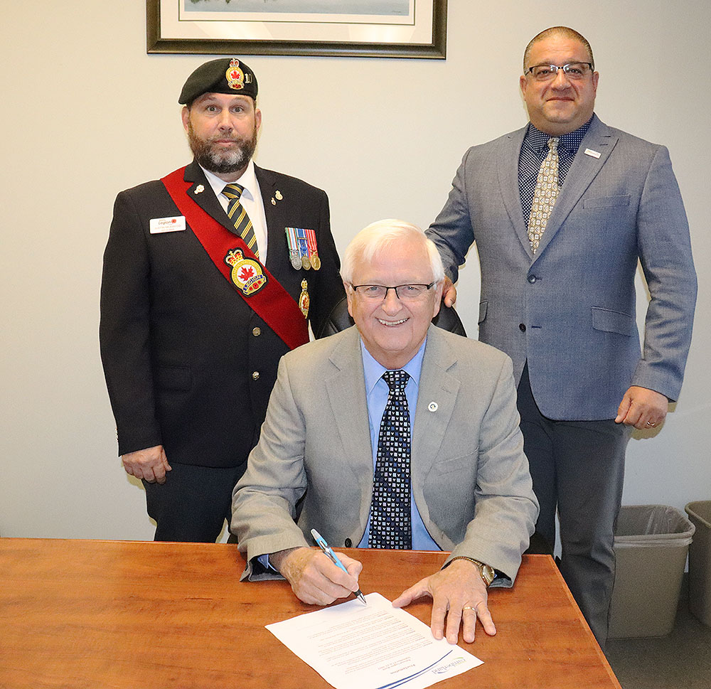 Mayor Murray Scott signs a proclamation declaring National Legion Week within the Municipality of Cumberland while Justin McKay and Deputy Mayor Mark Joseph look on.