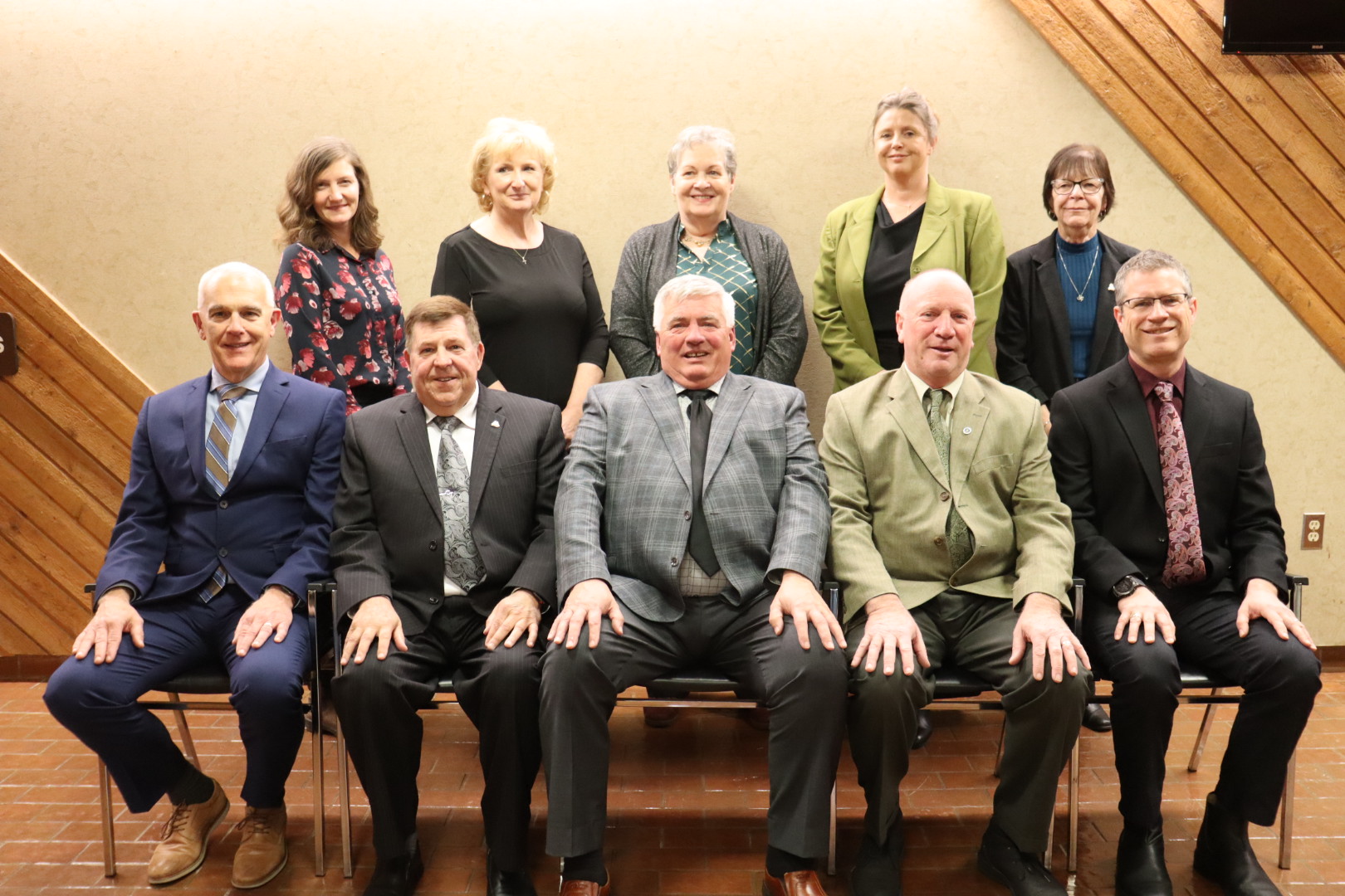 10 people, five women standing in back and five men sitting in front, pose for a photograph