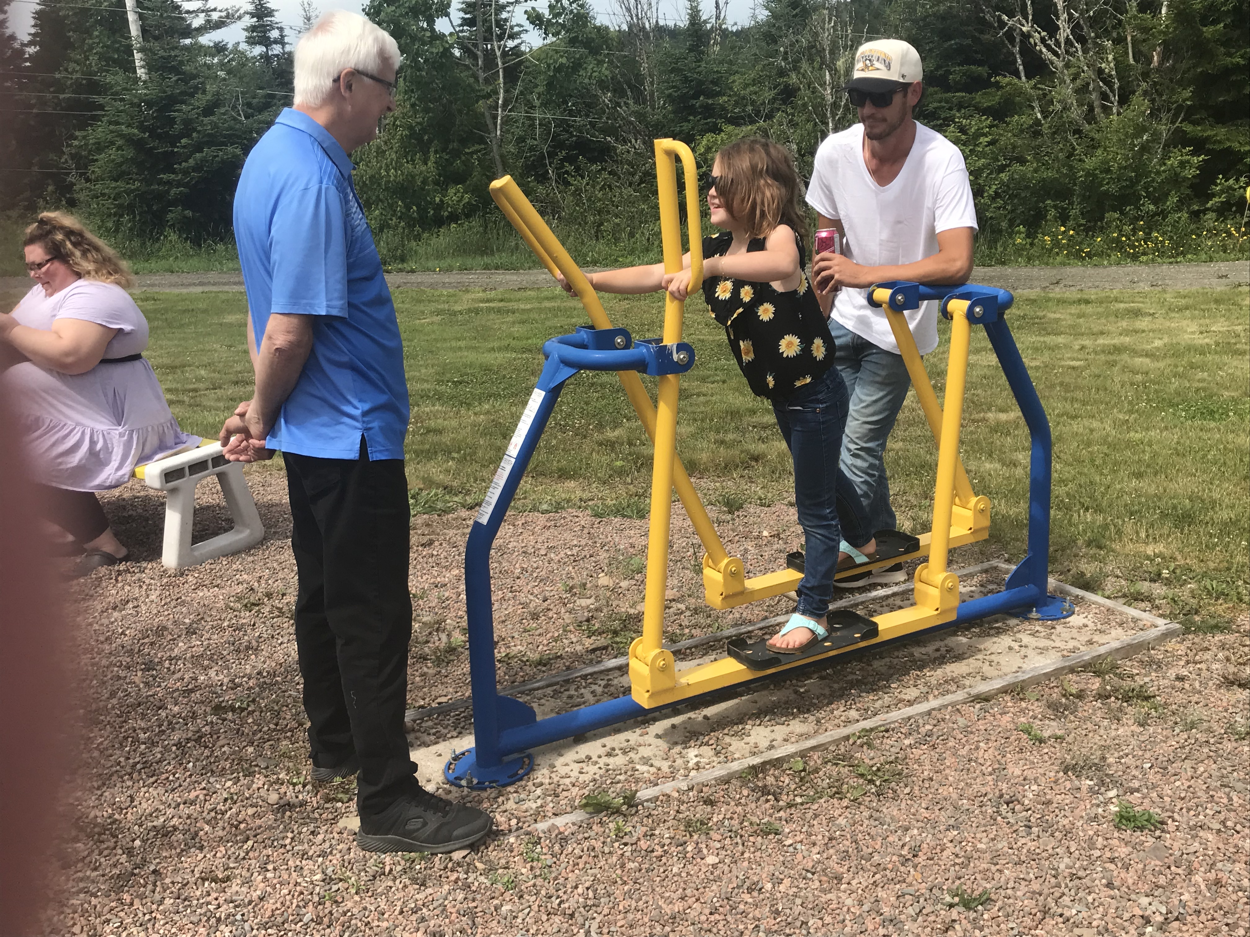 Municipality of Cumberland Mayor Murray Scott watches two people on a piece of fitness equipment at the new fitness park in Port Greville.