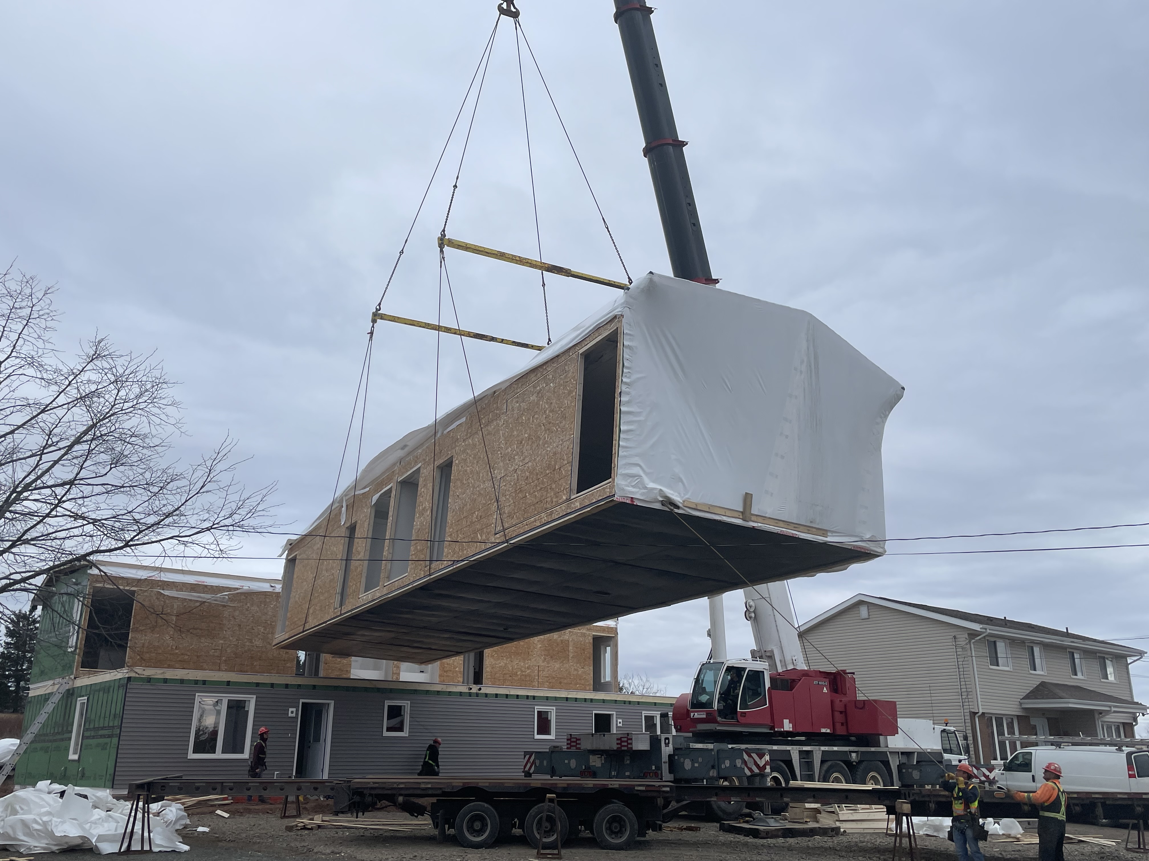 Workers ease a section of a four-section duplex into place on Mechanic Street in Springhill.