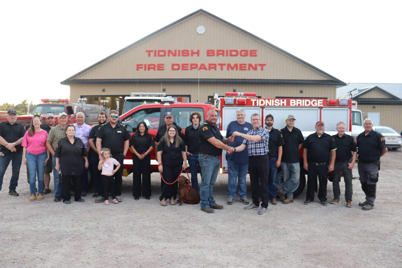 A group of people stand in front of a new rescue vehicle with the Tidnish Bridge Fire Department building in the background.