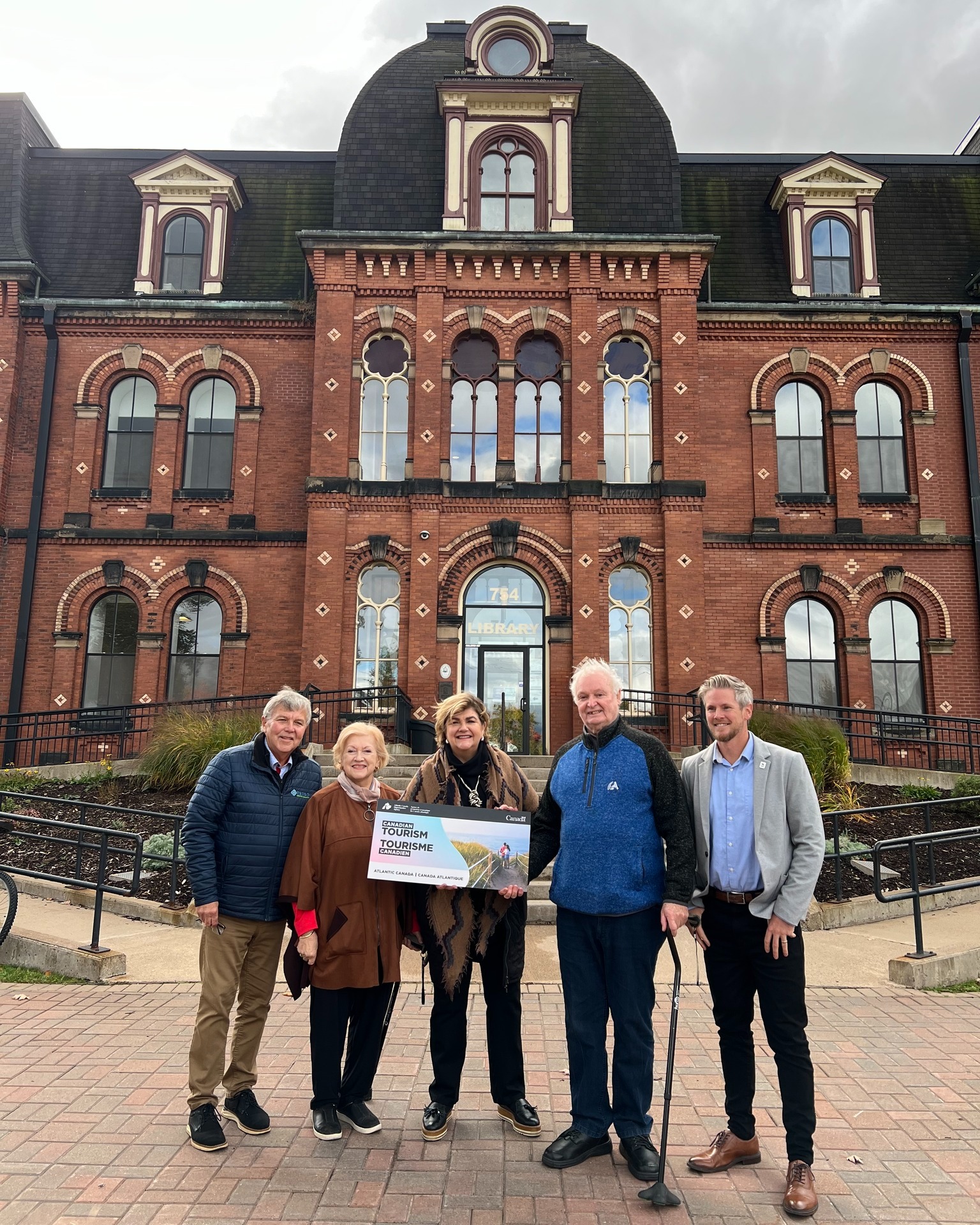 Five people stand in front of a building in Truro.